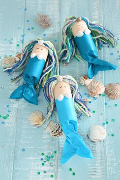 two little mermaids made out of paper and some sea shells