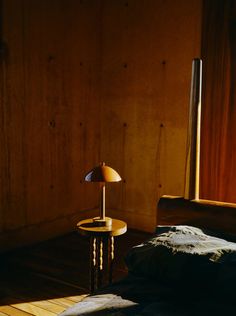 a bed with a lamp on top of it next to a wooden wall and floor