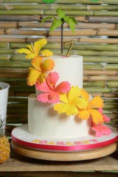 there is a cake with flowers on it and a pineapple next to the cake