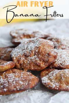 a pile of banana fritters sitting on top of a white table cloth with powdered sugar