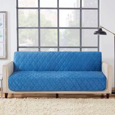 a living room with a blue couch in front of a window and rug on the floor