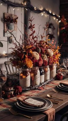 a table set for thanksgiving dinner with flowers in mason jars and place settings on the table