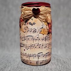 a jar with musical notes on it sitting on top of a gray cloth covered table