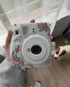 a person holding up a camera in front of a window with a dog on the other side