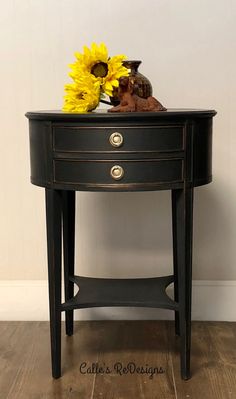 a black table with sunflowers on top and a small vase sitting on it