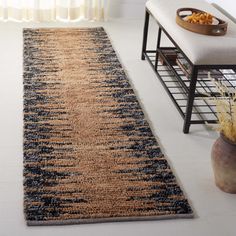 a large rug in the middle of a room with a bench and window behind it