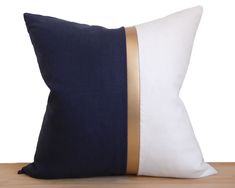 a blue and white pillow with gold trim on the side, sitting on a wooden table