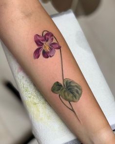 a woman's arm with a flower tattoo on it