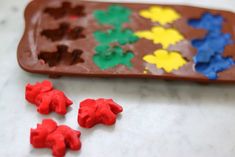 some red, yellow and blue gummy bears are next to a chocolate molding tray