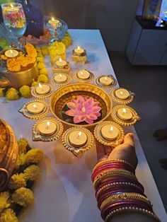 a person holding a plate with candles and flowers on it next to other items that are sitting on a table