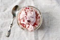 a small glass bowl filled with ice cream and cranberry sauce next to a spoon