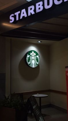 the starbucks logo is lit up in front of a sign that reads, starbuck