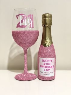 a pink wine glass next to a bottle with the word happy 21st birthday written on it