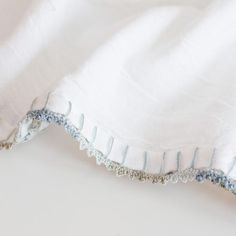 a close up of a white cloth with blue thread on the edge and an embroidered border