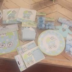 baby shower items are laid out on a wooden table with blue and green decorations around them