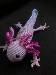 a crocheted gecko with pink and white flowers on it's body