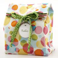 a colorful polka dot gift bag with a green ribbon tied around the front and bottom