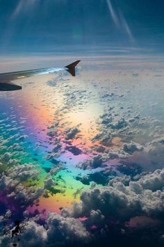 an airplane is flying over the clouds and rainbow