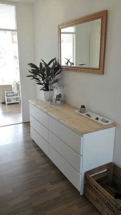 a white dresser sitting next to a mirror on top of a wooden floor in a room