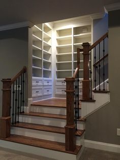 an empty room with stairs leading up to the second floor and storage units on either side