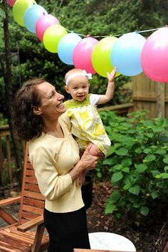 a woman holding a baby and balloons in her hand