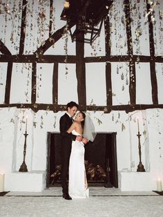 a bride and groom standing in front of a fireplace with candles on the mantles