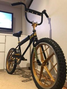 a black and gold bike parked in front of a flat screen tv