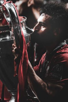 a man is kissing the trophy while wearing a red shirt and holding it in his hand