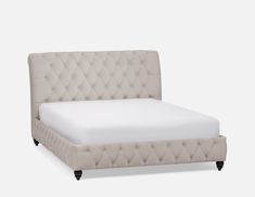 a white bed with tufted headboard and foot board is shown in front of a gray background