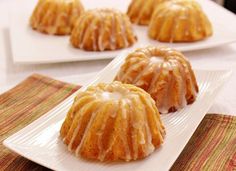 four glazed donuts on white plates sitting on a table