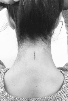 the back of a woman's neck with an arrow tattoo on it