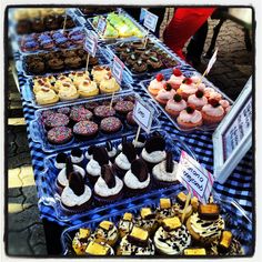 a table topped with lots of different types of cakes and cupcakes on top of plastic trays