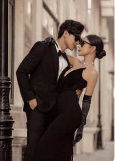 a man and woman in formal wear standing next to each other on a street corner