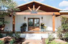 a white house with two large planters on the front porch and an entry way