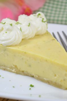 a piece of cheesecake on a white plate with a fork and flowers in the background