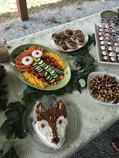 a table topped with plates and trays filled with food next to other desserts