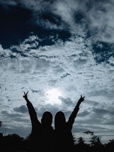 two people with their arms up in the air and clouds behind them, one person raising his hands