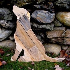 a wooden cat sitting in front of a stone wall