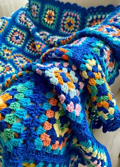 a blue crocheted blanket sitting on top of a white chair