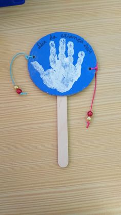 a paper plate with a handprint on it next to a string and bead