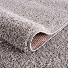 a close up view of a grey carpet with a white rug on the bottom right corner