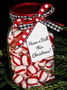 a jar filled with red and white candy canes on top of a green christmas tree