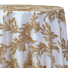 a white and gold table cloth with golden leaves on the top, in front of a white background