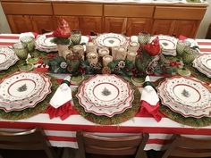 the table is set for christmas dinner with plates and napkins on top of it