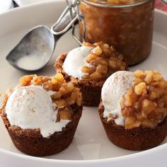 three cupcakes on a white plate with a spoon and jar in the background