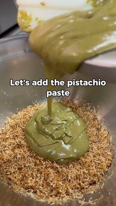 a metal bowl filled with green sauce on top of wood shaving