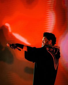 a man is performing on stage with his arms spread out to the side while wearing gloves