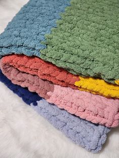 a pile of multicolored towels laying on top of a white furnishing