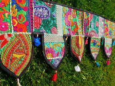 several colorfully decorated pieces of cloth hanging on a line in the grass with tassels attached to them