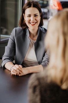 a woman sitting at a table smiling and talking to another woman